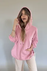 Canguro oversize color rosa con capucha, cordones blancos y bolsillo tipo canguro.