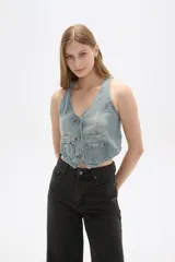 Chaleco de jean celeste sin mangas, con cuello en V, cierre frontal con botones y dos bolsillos con solapa en el pecho.