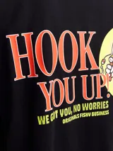 Camiseta negra de manga corta y cuello redondo con fit holgado. Estampa pequeña en el pecho con texto "Book You Up! Originals From Business".