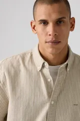 Camisa manga corta a rayas verticales color beige y blanco, con cuello abotonado y corte recto.