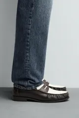 Mocasín de cuero color negro con antifaz en contraste blanco y marrón.