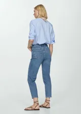 Pantalón de jean celeste, de corte mom-fit, tiro alto, con cinco bolsillos y cierre de cremallera y botón.
