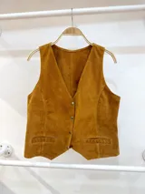Chaleco marrón de gamuza con cuello en V, cierre con botones y bolsillos frontales con detalle de costuras. Corte recto.