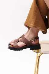 Sandalias marrones de cuero con suela track negra y hebilla plateada.