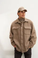 Camisa estilo leñadora marrón con diseño de espiga, cuello clásico, abrochadura frontal a la vista, bolsillos plaqué con tapa en el pecho, mangas largas con puño y botón.