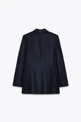 Blazer azul marino de cuello solapa y manga larga con hombreras. Tiene abertura en la espalda y cierre frontal cruzado con botones.