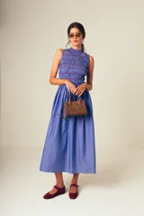 Vestido midi a rayas verticales azules y blancas, con cuerpo superior fruncido y falda amplia. Presenta un detalle de flor roja en el hombro.