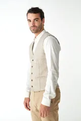 Chaleco de vestir para hombre, color marrón claro con textura tweed. Diseño sastrero con cuello en V, cierre frontal con botones, bolsillos ribeteados y forro interno. Confeccionado en lana fina sin teñir, diseñado exclusivamente por Don Baez.