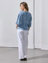 Blusa celeste con estampado floral blanco, escote en V y botones. Mangas 3/4 abullonadas con terminación elastizada.
