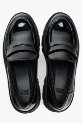 Zapato tipo mocasín negro acharolado con antifaz y suela track.