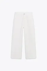 Pantalón cropped de tiro alto, color blanco, con corte recto, bolsillos delanteros y traseros, trabillas en la cintura y cierre frontal con cremallera y botón.