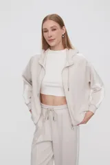 Campera con capucha color beige claro con cierre frontal y bolsillos laterales. Presenta una banda blanca en las mangas. Corte holgado.