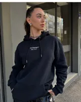 Canguro negro con capucha y bolsillo delantero, con inscripción 'BE TRENDY EST. 2022' en el pecho.