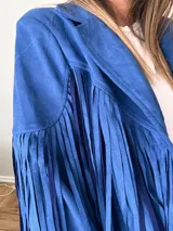 Campera de gamuza sintética color mostaza con flecos largos en mangas y espalda, corte recto con solapas clásicas.