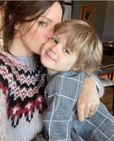 Sweater gris con diseño geométrico en negro y rojo alrededor del cuello, de lana tejido a mano con estilo nórdico.