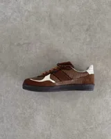 Sneakers bajas de cuero vacuno color bordó con suela marrón.