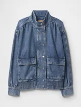 Campera de jean azul con corte bomber, cuello alto, cierre con botones a presión, mangas largas abullonadas con puños elásticos, bolsillos frontales con solapa y cintura elástica.