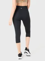 Calza capri deportiva negra de tiro alto con logo estampado en la cintura.