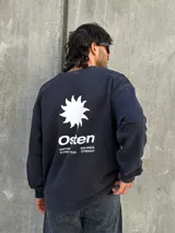 Buzo negro de corte holgado con estampa en la espalda que incluye una estrella blanca, la palabra "Osen" y las palabras "Empower", "Elevate", "Boldness" y "Strength".