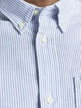 Camisa de vestir a rayas verticales celestes y blancas, de manga larga y cuello abotonado. Cierre con botones y corte slim fit.