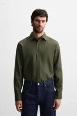 Camisa blanca de corte regular, cuello italiano, manga larga con puños abotonados y cierre frontal con botones.