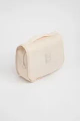 Neceser de viaje color beige con cierre de cremallera y asa de mano. Tiene un pequeño logo rectangular en el frente.