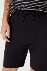 Bermuda verde de algodón con cintura elástica y cordón ajustable.