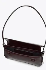 Bolso de hombro color crema con efecto acharolado, solapa con cierre magnético y asa ajustable.