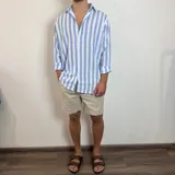 Camisa de lino a rayas verticales color beige y blanco, de corte holgado y manga larga con puños abotonados.