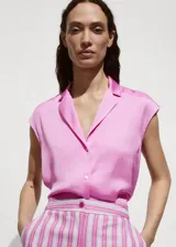 Camisa sin mangas color fucsia con cuello tipo camisa y botones frontales.