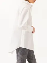 Camisa celeste de poplin, corte clásico, largo a la cadera y mangas largas. Cuello con detalle de piedras engarzadas. Cierre frontal con botones de pasta al tono.