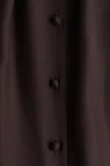 Vestido corto marrón oscuro, estilo túnica, con escote redondo amplio y botones forrados en el frente. Presenta mangas globo largas estilo raglán con puños elásticos y un fruncido escalonado bajo la cadera que le da volumen.