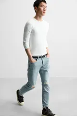 Pantalón de jean negro con corte skinny fit, cinco bolsillos, lavado con efecto roto y cierre frontal con cremallera y botón.