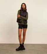 Chaleco puffer deportivo negro confeccionado en poliamida, con cuello alto y cierre frontal con cremallera. Incluye bolsita para guardarlo.