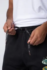 Pantalón de jogging negro de corte oversize, con puños elásticos y estampado con la palabra 'FUTURO' en verde y amarillo.