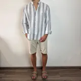 Camisa celeste y blanca a rayas verticales, de lino, con cuello mao y mangas largas con puños.