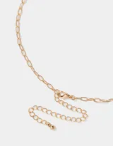 Collar dorado con cadena de eslabones y dijes colgantes: fósforo con cabeza roja, naipe con corazón y dado esmaltado rosa.