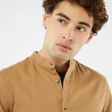 Camisa color beige de manga corta con cuello mao y cierre frontal con botones.