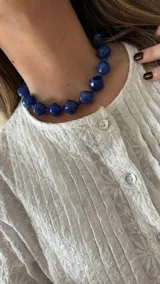 Collar corto de cuentas facetadas de color azul con cuentas más pequeñas entre las grandes.