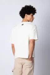 Remera color crudo de corte cuadrado y holgado, con cuello redondo y mangas cortas. Confeccionada en algodón pesado.