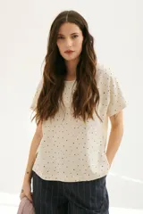 Blusa color crema con estampado de lunares negros, cuello redondo y mangas cortas.