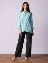 Camisa celeste texturada con cuello con solapa y abertura central con botones. Delantera con bolsillo aplicado y largo de manga regulable con presilla y botón.
