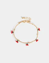 Pulsera flexible dorada con doble cadena, una de mostacillas transparentes y otra de metal, con dijes de cerezas rojas y verdes.