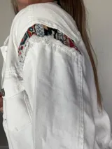 Campera de jean oversize, color rojo desgastado, con aplicaciones de tapicería multicolor de estilo étnico en hombros y ruedo, y terminaciones desflecadas.