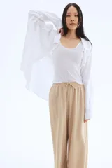 Pantalón de punto color beige, de corte holgado con piernas amplias, tiro alto, cintura elástica y cordón para ajustar.