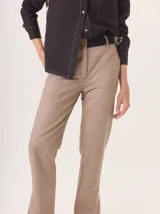 Pantalón de vestir color marrón, corte cigarette (pierna angosta) con tajo en el bajo. Presenta una cintura elástica ancha de color beige claro.