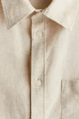 Camisa color crema en mezcla de lino y algodón, de corte regular fit, manga larga con puños abotonados, cuello inglés, tapeta clásica, canesú en la espalda, bolsillo superior abierto y bajo redondeado.