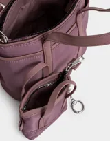 Cartera tipo tote color beige, de tela deportiva, con doble asa corta y correa larga regulable y desmontable. Tiene un bolsillo lateral con forma de pouch.