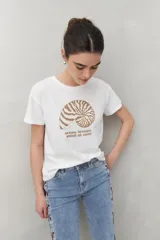 Remera blanca de manga corta con estampado de una concha marina y la frase "ocean breeze, mind at ease" en color marrón.