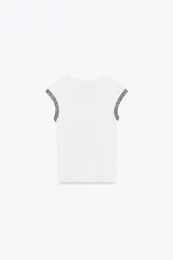 Camiseta blanca de cuello redondo y sisa con ribete de hilo metalizado en contraste en las mangas.